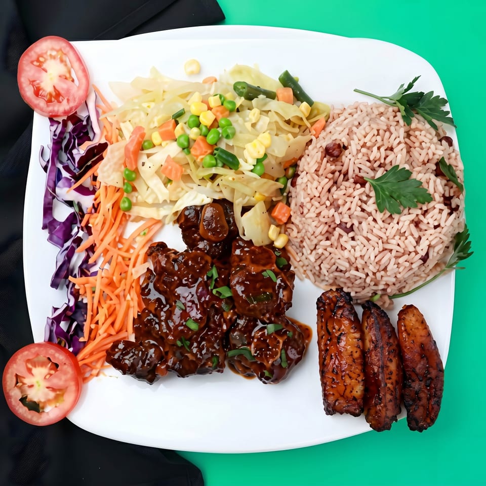 A white plate with oxtail, rice and peas, steamed vegetables, and three fried plantains.